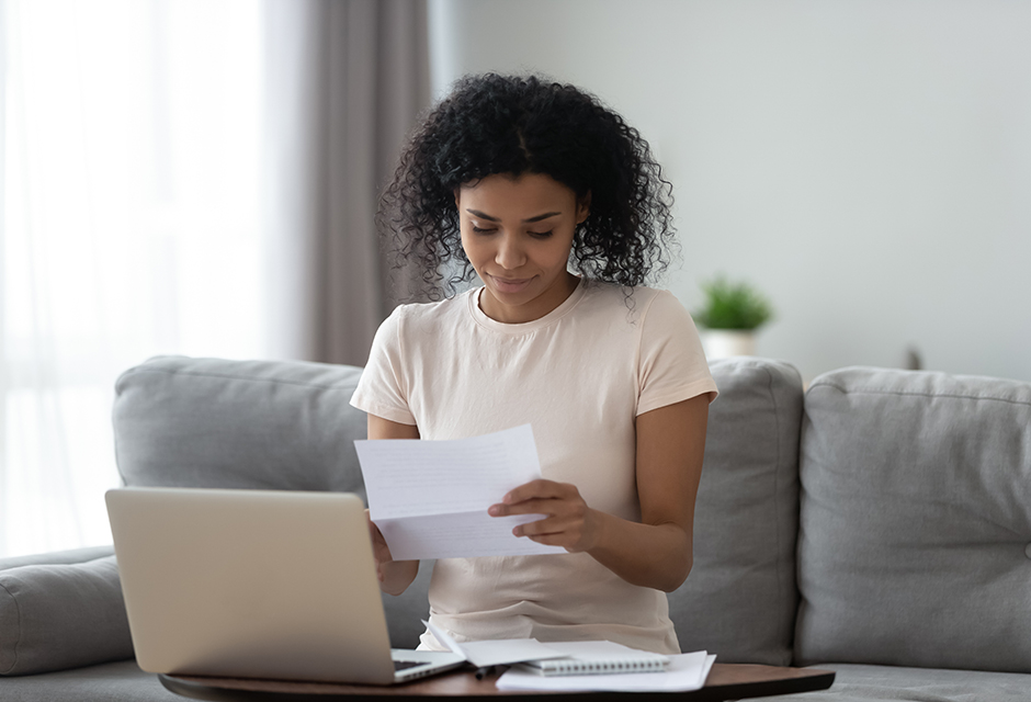 Woman reviewing paperwork beside a laptop, reflecting how tax professionals trace Form 1099-PATR patronage dividends to the underlying transaction.