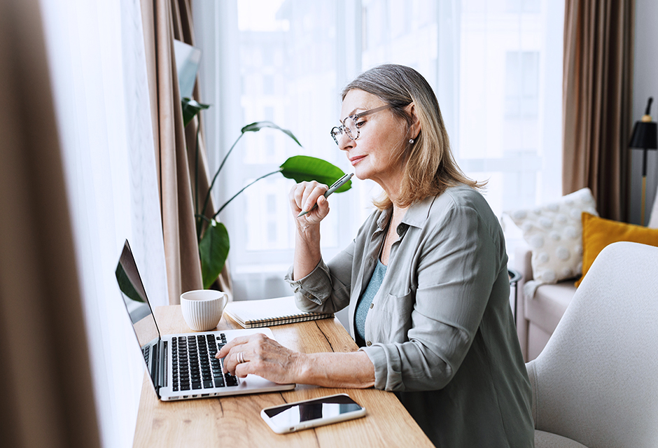 Woman reviewing information on a laptop with a pen and notebook while preparing for 2026 tax changes
