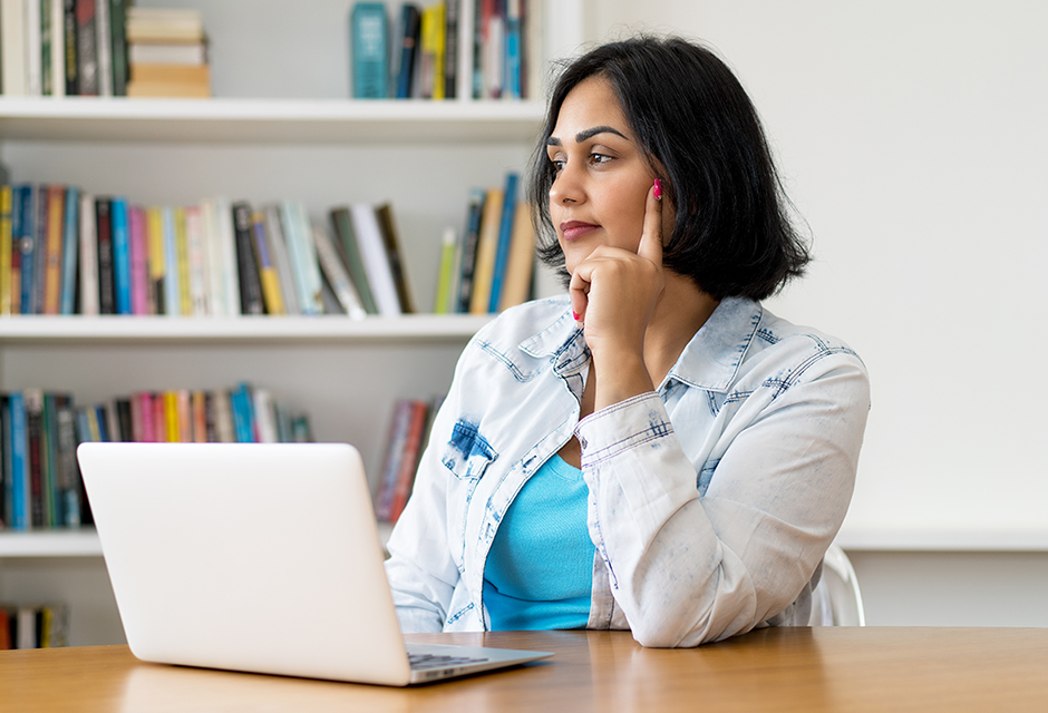 Thoughtful woman at a laptop considering inconsistencies in a client’s tax return fact pattern.