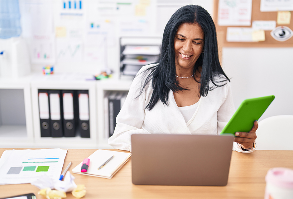 Woman reviewing financial documents and bond income details at a laptop in an office.