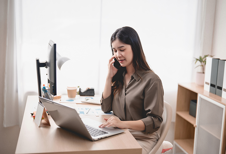 Tax professional working at a laptop while discussing the IRS FIRE-to-IRIS filing transition by phone.