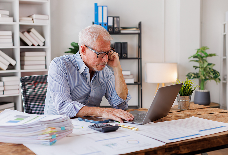 Tax professional reviewing partnership liquidation paperwork with laptop, calculator and documents for final Form 1065 filing