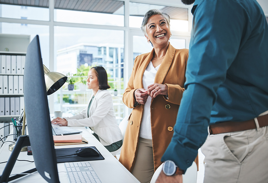 Tax firm staff discussing client matters in an office while a team member works at a desktop computer
