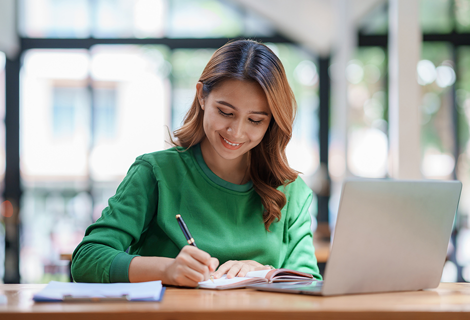 Tax professional reviewing estimated tax penalty guidance while taking notes beside a laptop