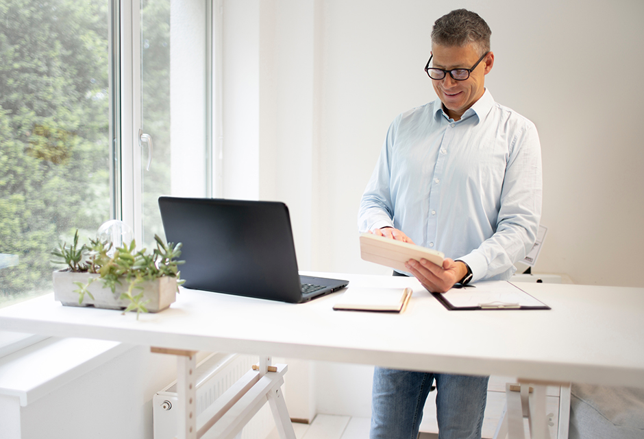 Tax professional reviews financial documents beside a laptop while determining whether a client needs Schedule B.