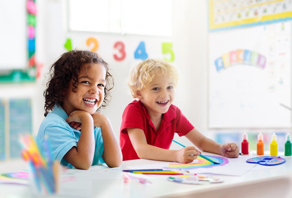 Two young children completing classroom activities, reflecting Form 2441 child and dependent care expense considerations.