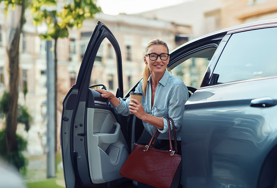 Tax professional leaving her car with coffee and a work bag on the way to an in-person Tax Season Updates workshop