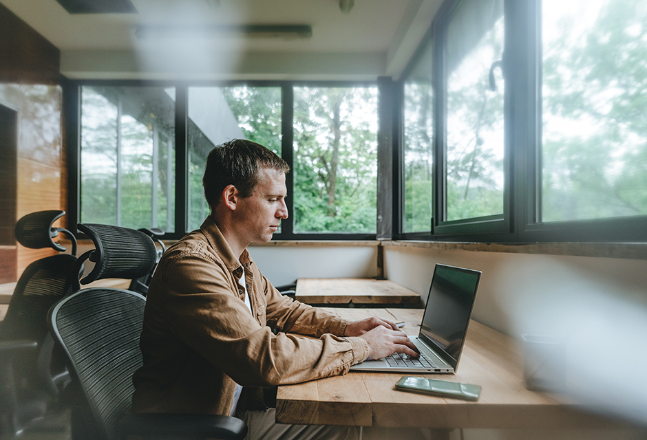 Man working on a laptop in a home office, reflecting careful AI-assisted tax research and professional review.