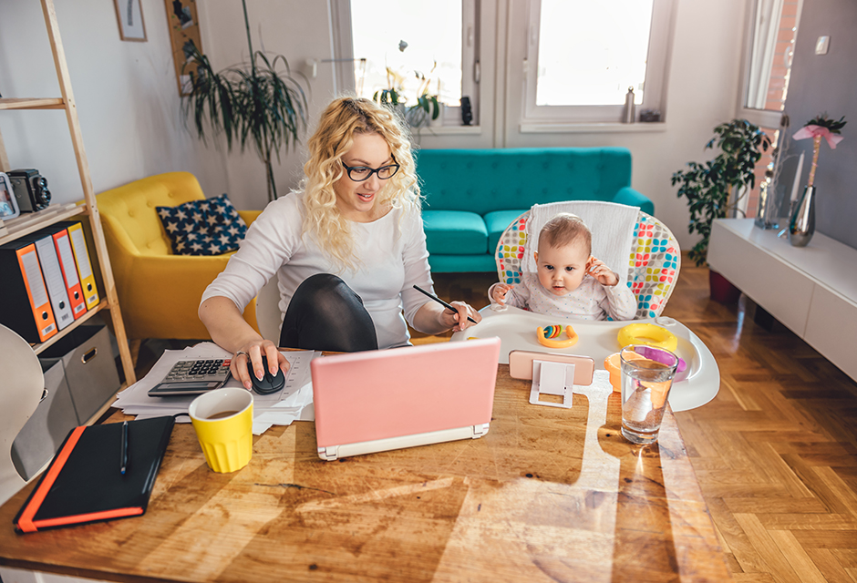 Parents review tax paperwork at home while their young children play nearby