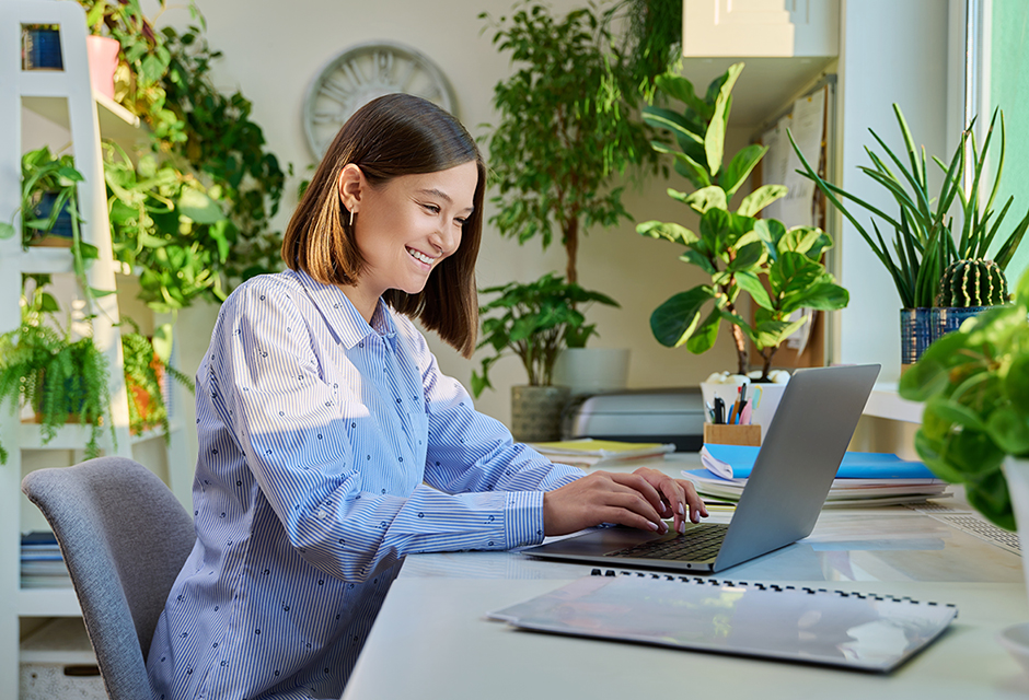 Tax professional working on a laptop in a bright, plant-filled office while planning website improvements before busy season.