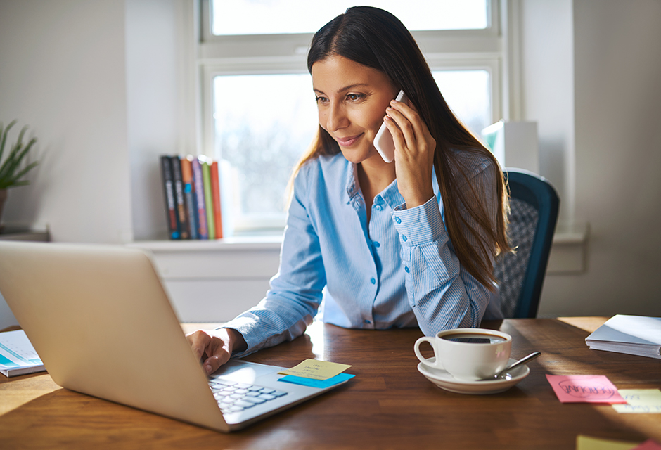 Tax professional discusses retirement rollover guidance by phone while working at a laptop.
