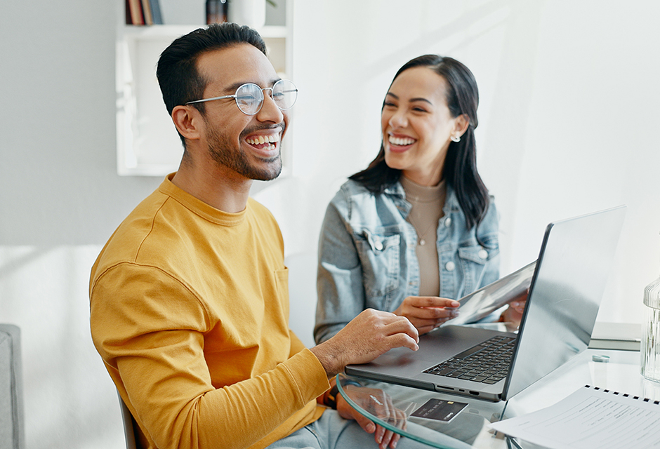 Small-business partners reviewing financial documents while working together on a laptop