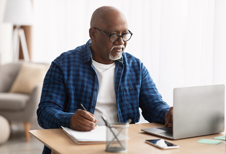 Man studying at a laptop with notes while preparing to become an enrolled agent