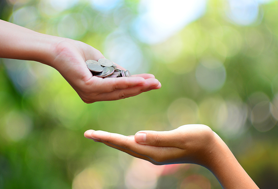 One hand offers coins above another open hand, representing the Saver’s Match retirement savings incentive.