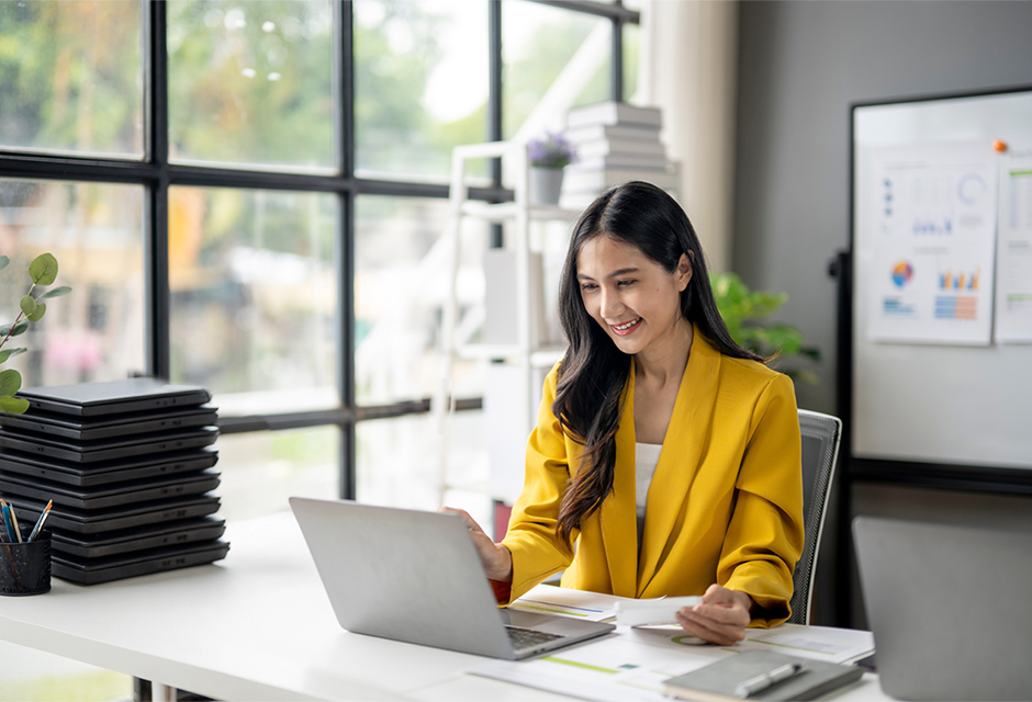 Woman in a yellow blazer reviewing paperwork beside a laptop, illustrating IRS e-file authorization and attachment requirements.