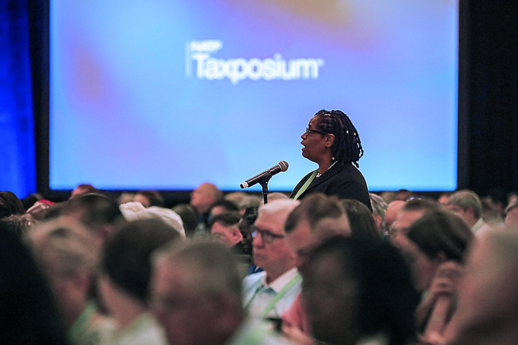 Tax professional asking a question into a microphone during a Taxposium conference session
