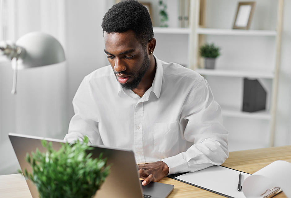Tax professional reviewing information on a laptop at his desk, illustrating the process of safely ending a tax client engagement.