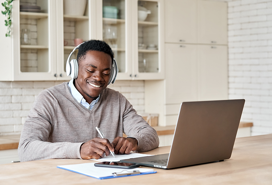 Tax professional wearing headphones reviews notes beside a laptop while learning how to correct missed depreciation.