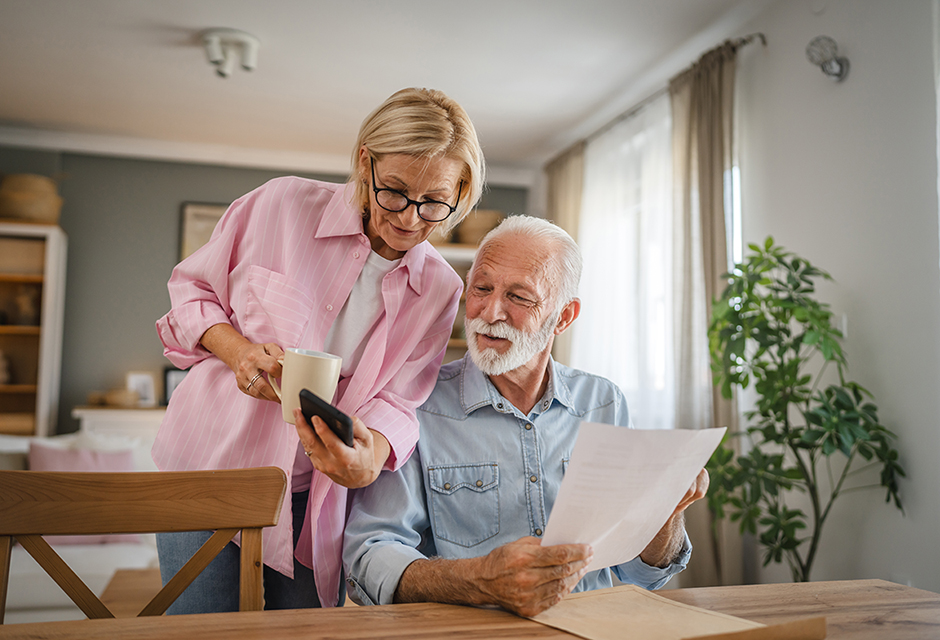 An older couple reviews financial paperwork at home, reflecting retirement tax planning around Social Security benefit taxability and income decisions.