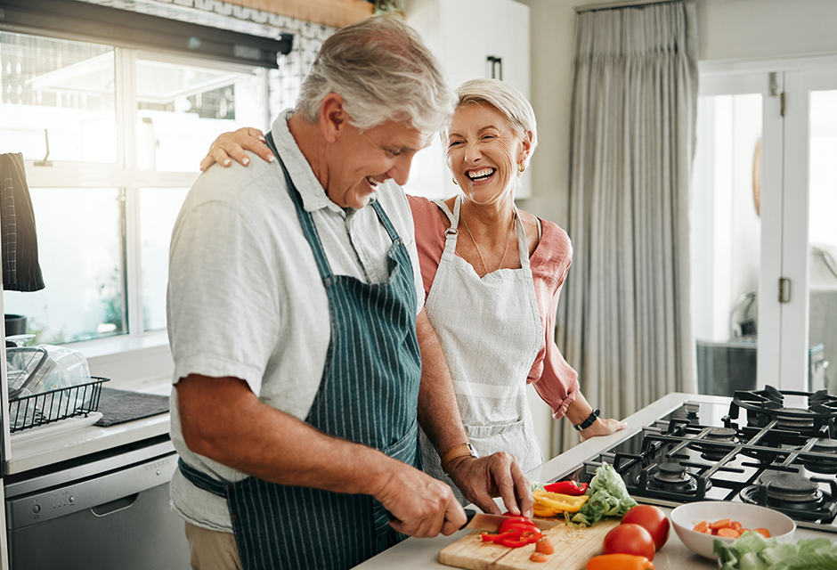 Older couple preparing vegetables together in a kitchen, reflecting retirement planning decisions around Social Security benefit timing and taxes.