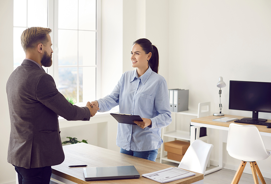 Two professionals shake hands over sale documents in an office, reflecting installment sale reporting and planning.
