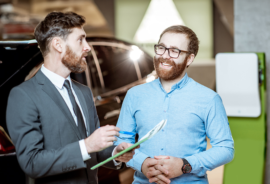 Two men discuss paperwork beside a vehicle, illustrating the recordkeeping involved in partnership property distributions and Form 7217.
