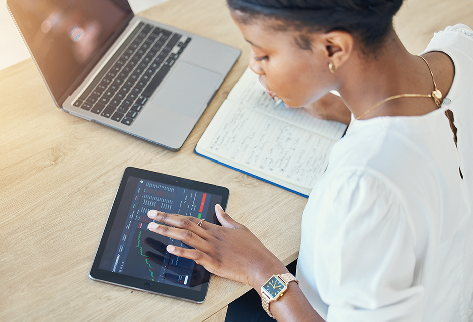 Tax professional reviewing digital asset records and market data on a tablet while reconciling basis information for tax reporting.