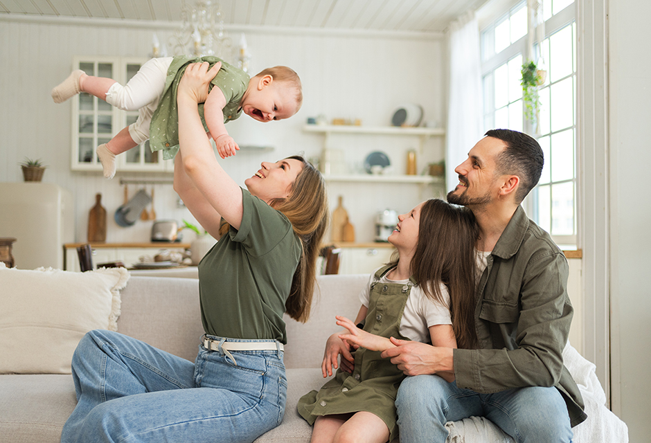 Two adults play with two young children at home alongside information about the 2026 adoption tax credit.