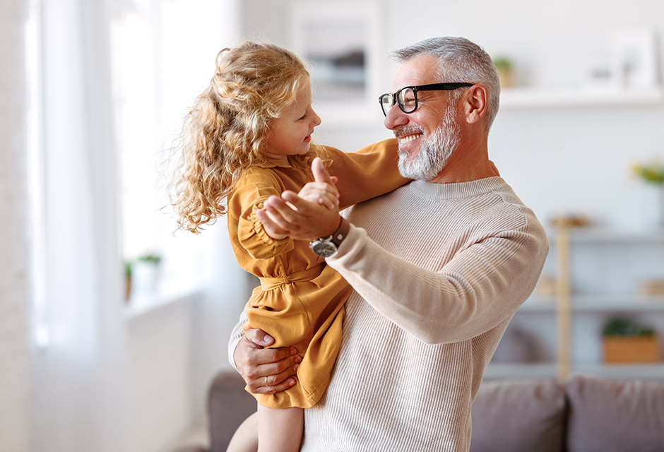 Grandfather holding his young granddaughter, reflecting how families can use Trump Accounts to build financial security across generations.