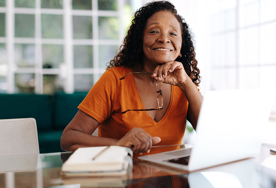 Smiling tax professional in an orange blouse at a laptop reviewing disaster and Ponzi scheme loss rules