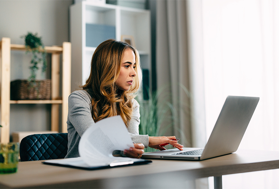 Tax professional reviews paperwork beside a laptop while reconciling records for employee stock options and other equity compensation.