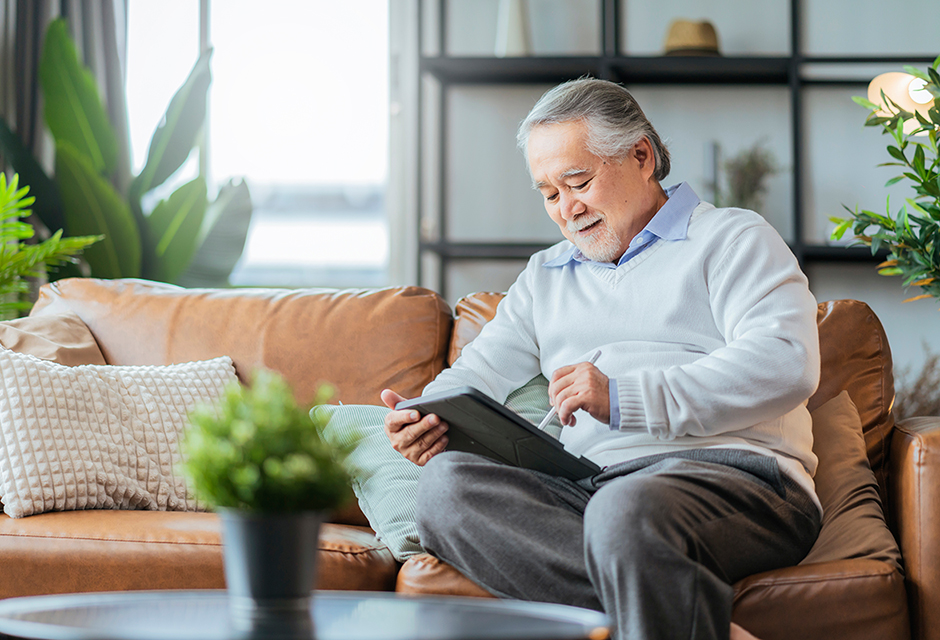 Older man reviewing information on a tablet at home, illustrating self-employment tax considerations for partners.