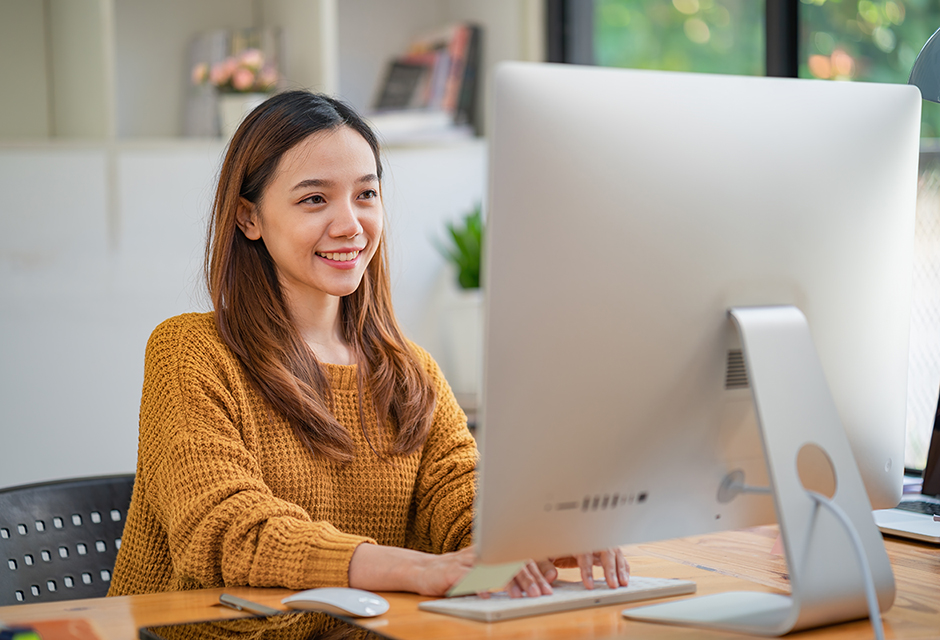 Smiling employee working at a computer, illustrating the tax consequences of exercising nonqualified stock options without selling shares.