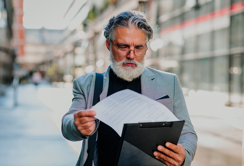 Business owner reviewing corporate liquidation paperwork in a warehouse setting with business assets and final tax reporting considerations.