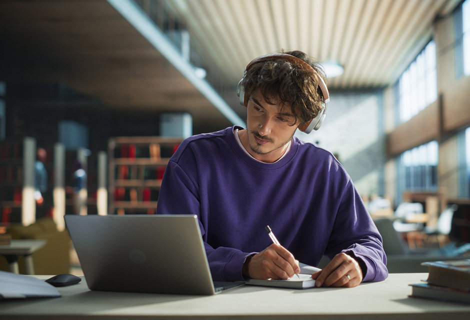 A student writes notes beside a laptop in a quiet study space, reflecting preparation for the enrolled agent exam.