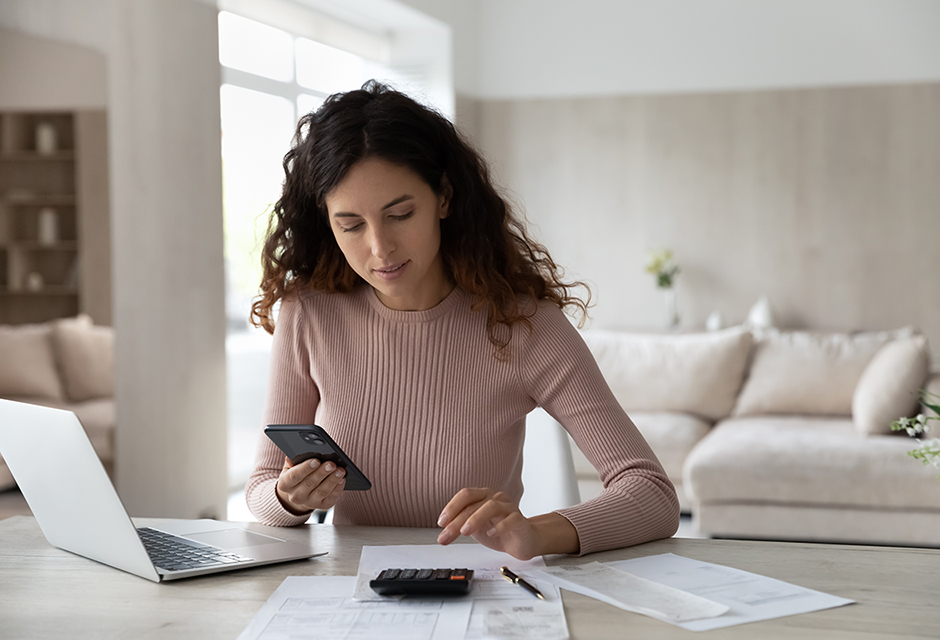 Solo tax practitioner reviews paperwork with a calculator and laptop before releasing a return.