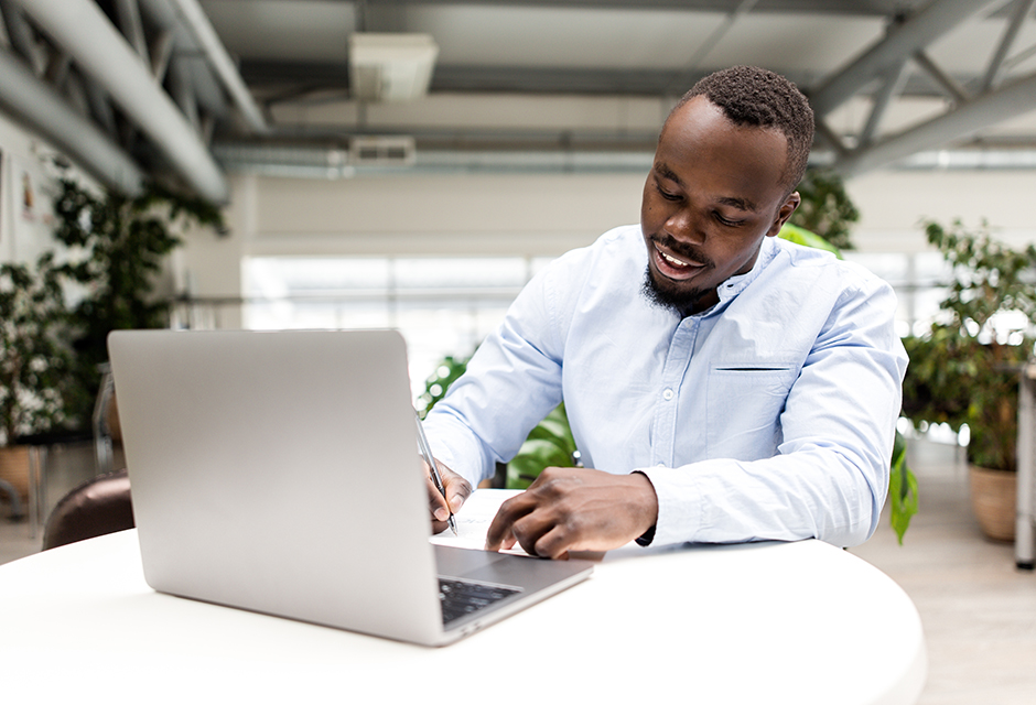 Tax professional taking notes beside a laptop while exploring AFSP education and career advancement.