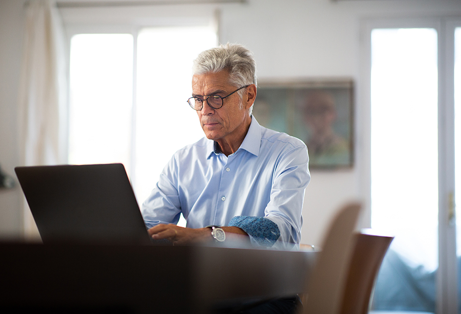 Older tax professional reviewing records on a laptop, reflecting the careful reporting required to complete a corporate liquidation.
