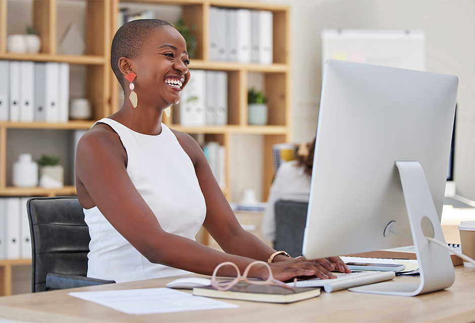 Tax preparer smiling while working at an office computer, illustrating worker classification issues for seasonal tax firm staff.