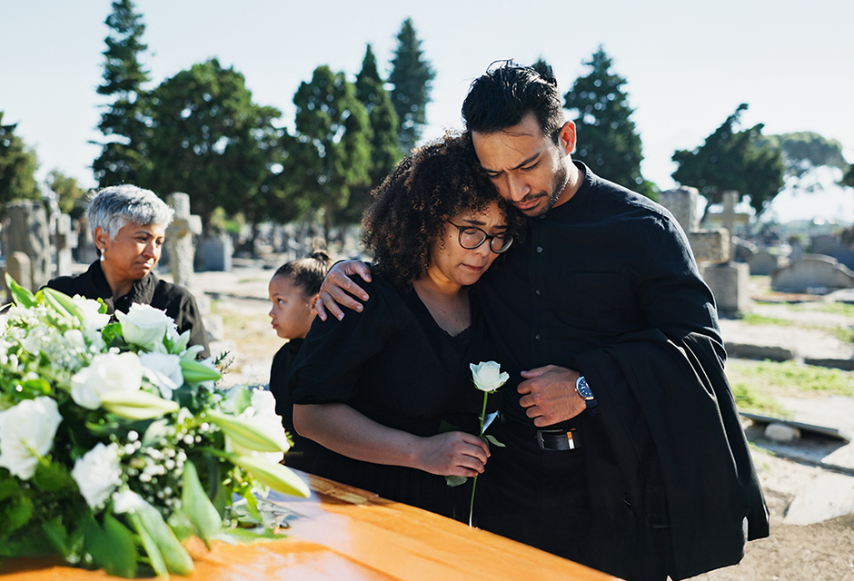Grieving family beside a casket at a cemetery, reflecting the loss behind qualifying surviving spouse tax filing questions.