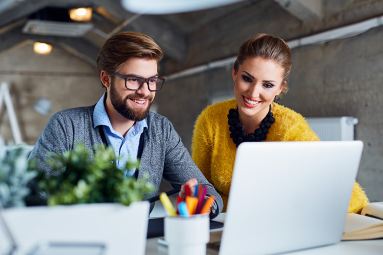 Two professionals collaborating at a computer with NATP mission to support members and provide reliable tax resources.