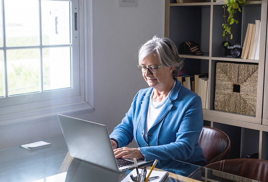 Tax professional reviewing S corporation reasonable compensation rules on a laptop while preparing payroll and distribution compliance from a home office.