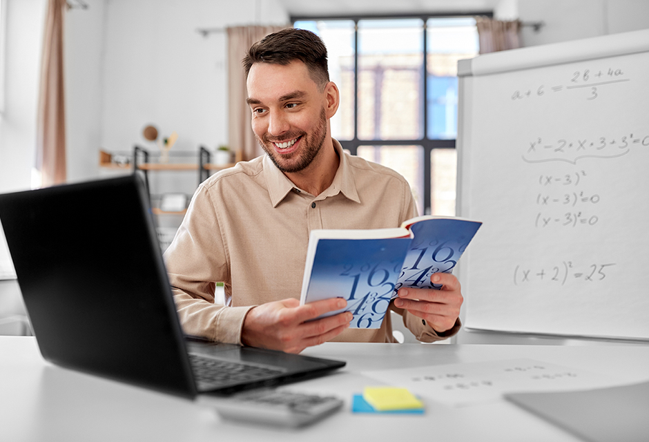 Self-employed tutor reviews math materials at a desk with a laptop, illustrating small business income and QBI deduction eligibility after OBBBA changes.