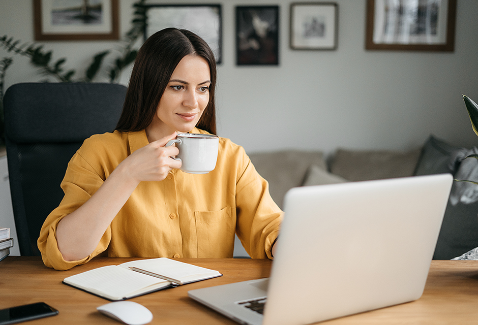 Woman working at a laptop with a mug in hand while reviewing C corporation IRS payment instructions on screen